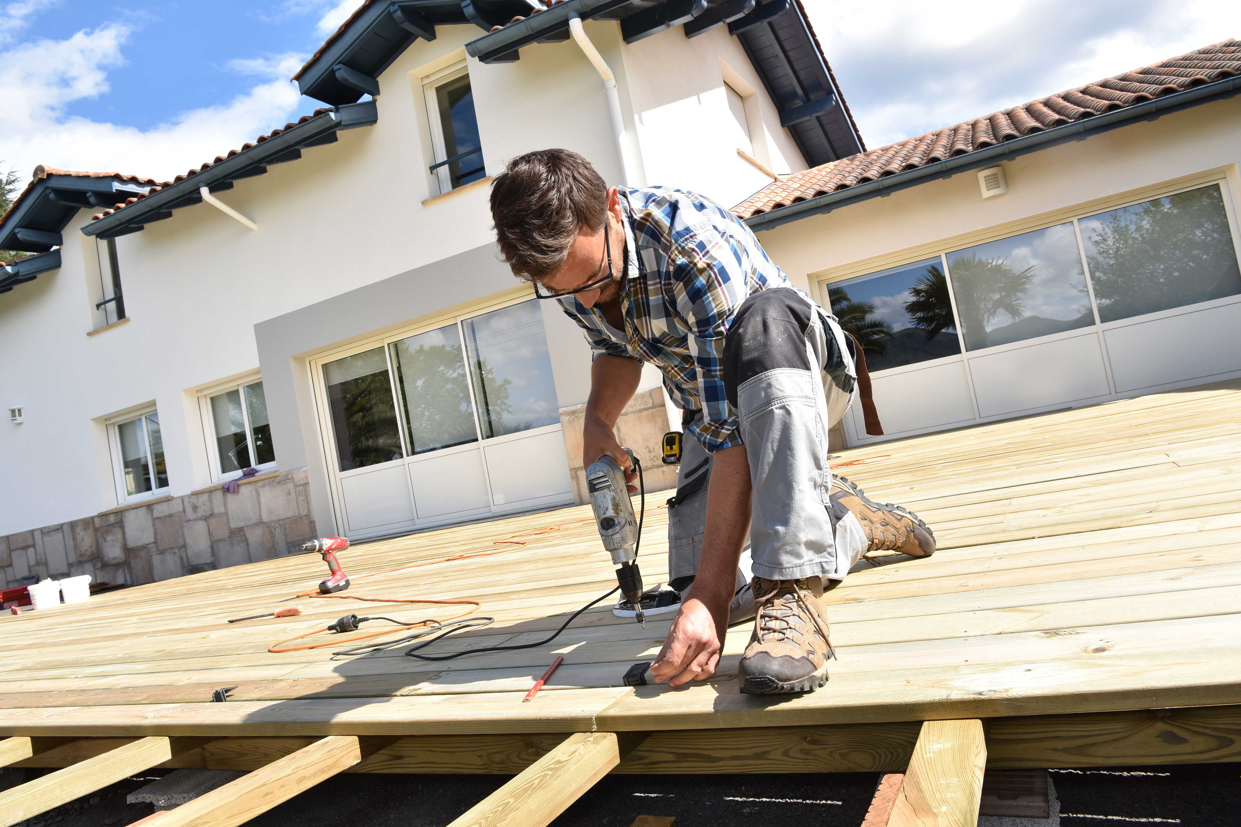Construction worker installing wooden deck boards on residential home patio